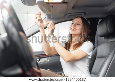 Car interior cleaning, girl worker installs perfume bottle.