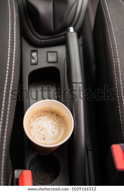 Car interior with a coffee to go placed in cup\
holder between seats in a\
car