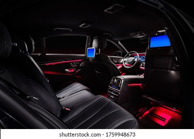 Car Interior With Comfortable Black Leather Seats, Displays And Red Ambient Light.