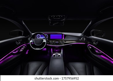 Car Interior From Driver Seat View. Black Leather Cockpit With Violet Ambient Light.