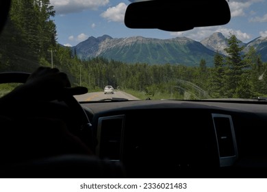 Car interior in front can landscape of calgary mountains big trees snowless mountains black road pickup truck in front - Powered by Shutterstock