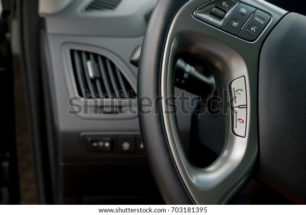 Car interior, on the black\
leather of steering with hands free buttons green and red ,\
telephone symbol and mode of volume, modern car interior for safety\
driver.