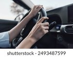 car interior showing a person driving with one hand on the steering wheel while the other adjusts the car controls, emphasizing focus and control