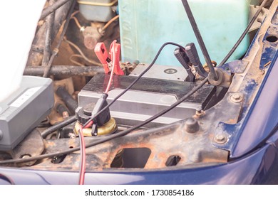 Car With Internal Combustion Engine. The Hood Is Open And The Battery Is Being Serviced.