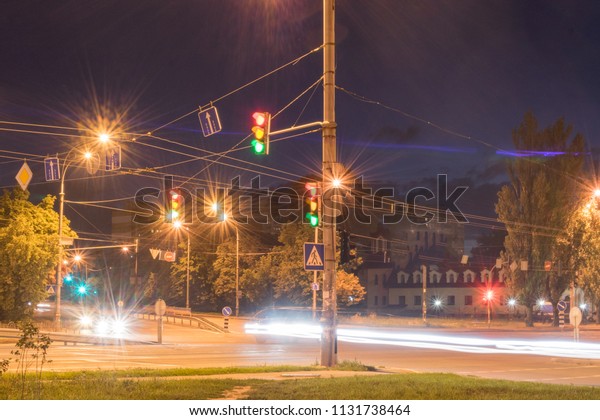 Car intersection with traffic lights and\
passing cars at night with long\
exposure.