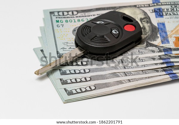 Car key and 100\
dollar bills cash. Concept of vehicle purchase cost, loan, repair,\
maintenance and expenses