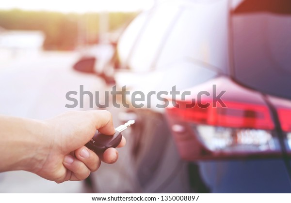 Car key in business man hand.\
hand presses on the remote control car alarm systems\
backside.	