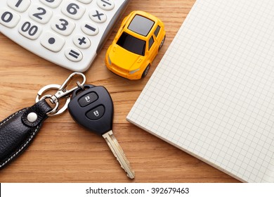 Car key with calculator and blank notebook on wood table
