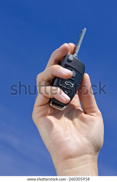 car key in hand on\
blue sky background