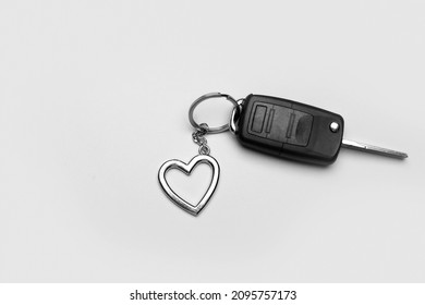 Car key with heart shape keychain on grey background
