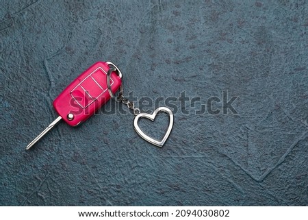 Car key with heart shape keychain on dark background