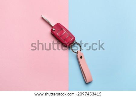 Car key with leather keychain on color background