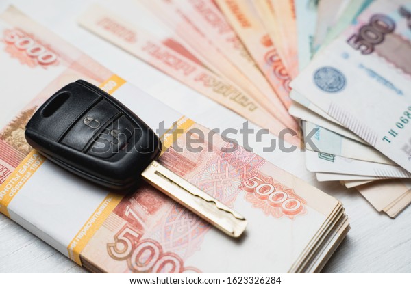 car key lies on a bundle with rubles banknotes,\
packs of rubles and a car\
key