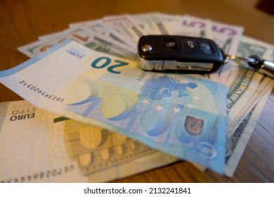 Car key lying on a bundle of dollar bills. Increase in fuel prices resulting in higher expenses related to the use of the car.