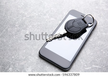 Car key and mobile phone on grey table