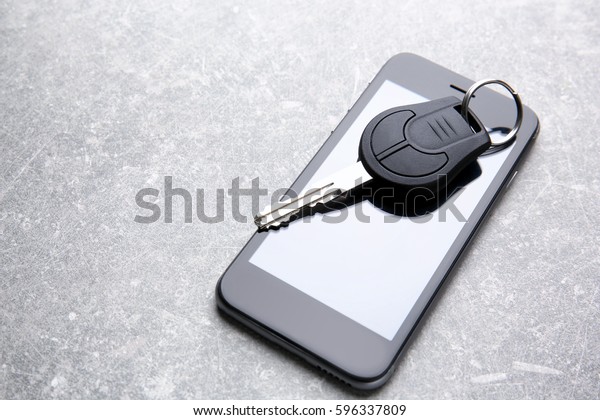 Car key and mobile\
phone on grey table