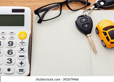 Car key on blank notebook with calculator on wood table