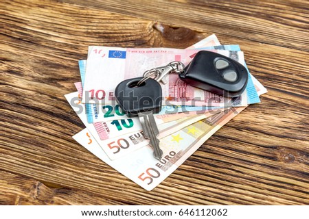 Car key with remote control and euro bills on the table.