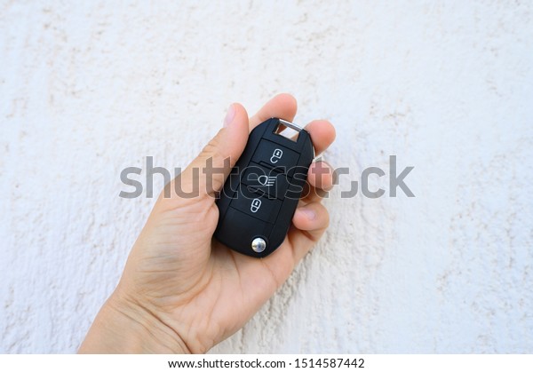 car key with remote control in female hand on\
white textured background