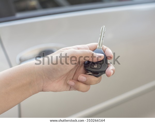 A car key\
remote control in the hand, Use the remote control to open the car\
door, car safety security\
system.