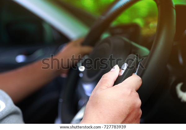 Car key remote.Hold in hand.Men driving.Focus on\
finger press.Backdrop\
blurred.