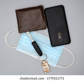 Car Key, Surgical Mask, Leather Wallet And Mobile Phone On Gray Background.