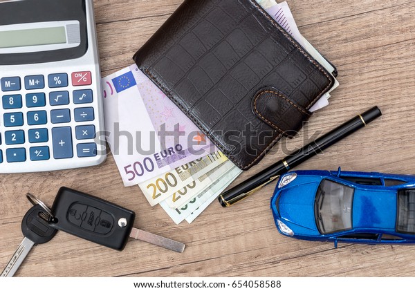 car key, toy car, euro\
bills on desk.
