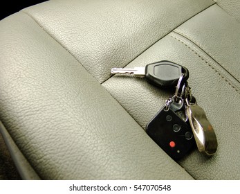 Car Keys With Alarm Remote And Pendant On The Background Of Front Leather Seat Of A Luxury Car