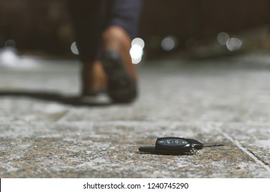 Car keys dropped from a woman pocket on the night footpath and her silhouette is walking away.