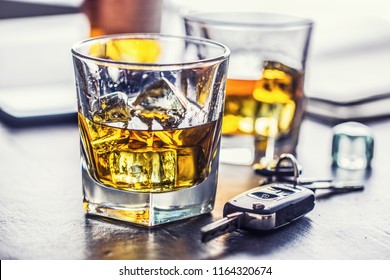 Car keys and glass of alcohol on table in pub or restaurant.
