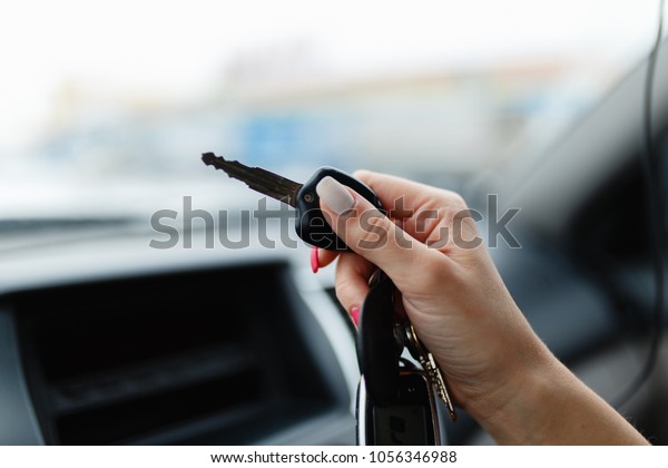 Car keys in the hand of a girl in the\
car interior. Woman holding car keys. Close up\
Hand