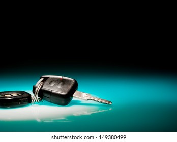 Car keys on blue, reflective table and black background