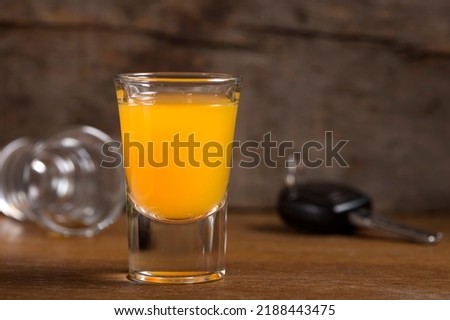 Car keys with one shot glasses over wood background - drink drive concept