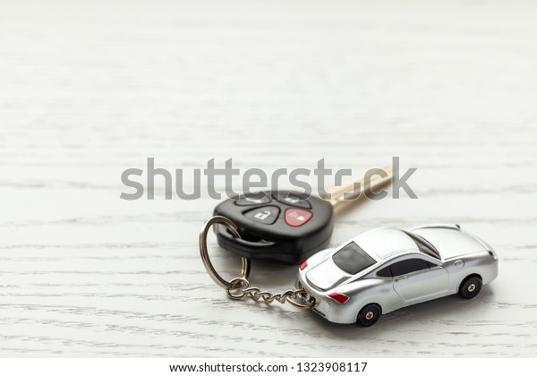 Car keys with remote\
control security and car key chain on white wooden background. Copy\
space for text.