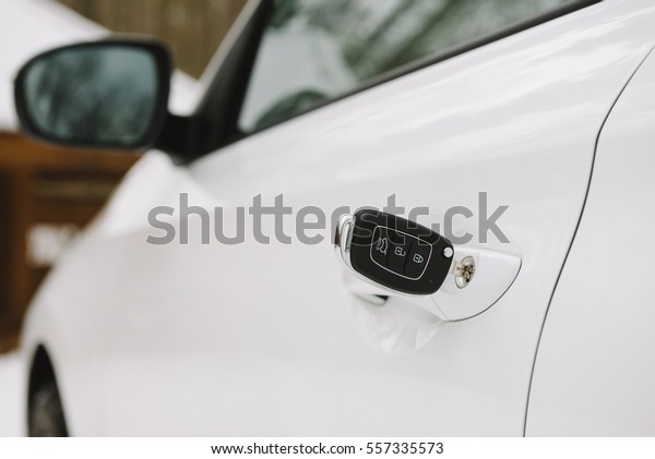 Car keys in white door lock closeup with copy\
space. Opening car door with\
key