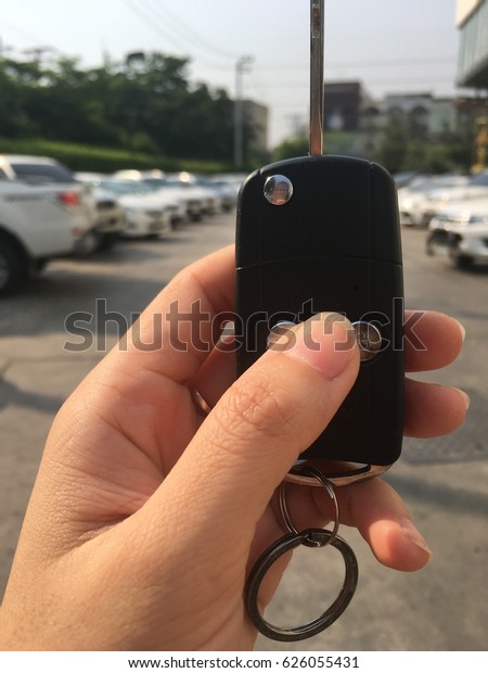 Car keys in women left hand who\'s looking her car in\
parking area