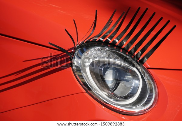 Car Lamp Detail, Black\
Eyelashes Decoration. Red Car on The Street in Stuttgart City of\
Germany.