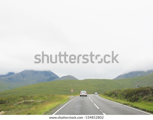 A car landing, road view at Highlands,\
Scotland. Mountains\
background.