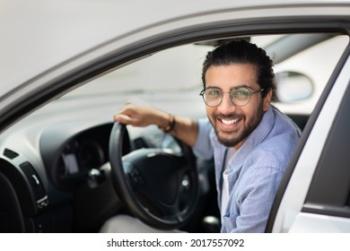 Car Leasing, Buying, Retail, Renting Concept. Portrait Of Happy Arab Guy In Casual Outfit Getting Into Brand New Auto, Placing Hand On Wheel, Cheerfully Smiling At Camera, Side View, Copy Space