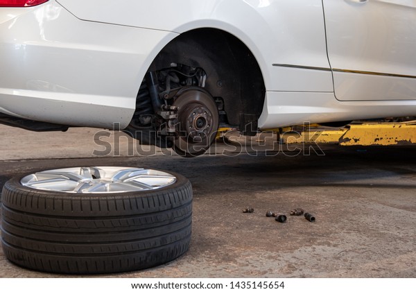 Car Lifted In Auto-Repair Service For Fixing And\
Tire Lay Down On Floor.