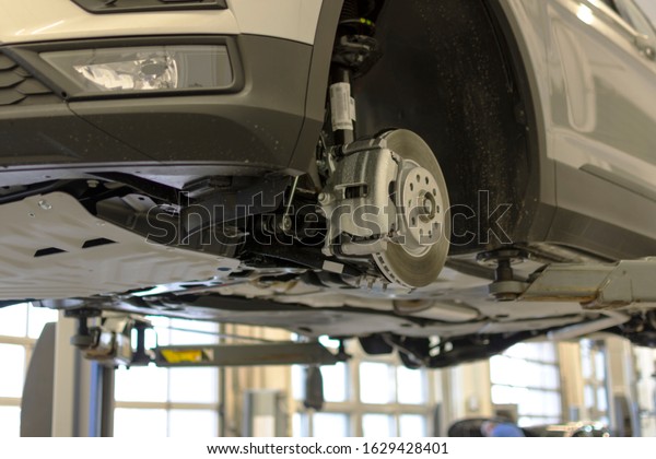 Car lifted on a lift for repair in a car\
service. Brake system of a modern\
car.