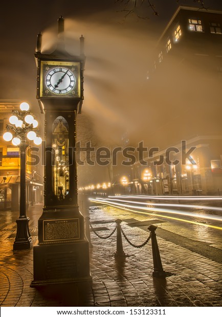 Car light streaks next to Gastown steam clock\
in Vancouver