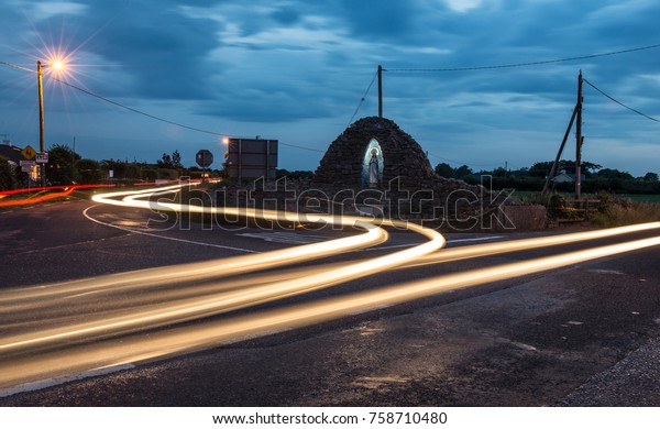 Car\
light streaks  on a holy crossroads in rural\
Ireland
