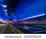 Car light trail by a modern building illuminated with blue lights. Road to Dublin airport terminal. Night shot. Transport and traffic.