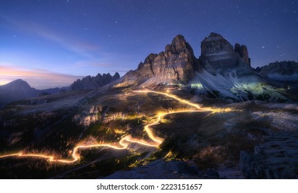 Car light trails on mountain road and high rocks at night in autumn in Tre cime, Dolomites, Italy. Colorful landscape with blurred light trails, hills, mountain peaks, sky with stars in fall at sunset - Powered by Shutterstock