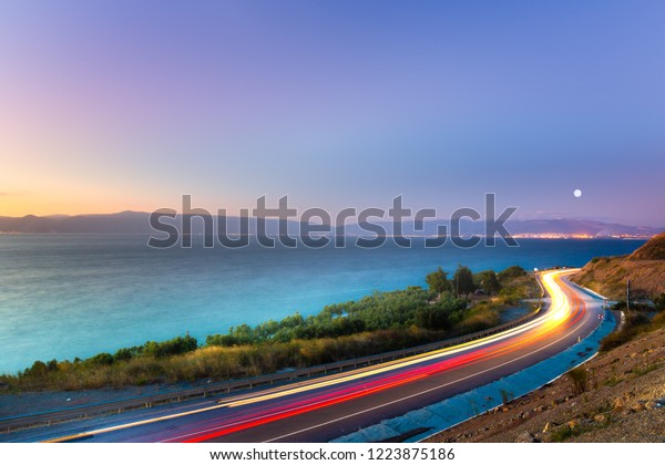 Car
lights and coastal path at sea shore. Car lights on the road near
the coast. Coastal highway. Mudanya, Bursa, Turkey

