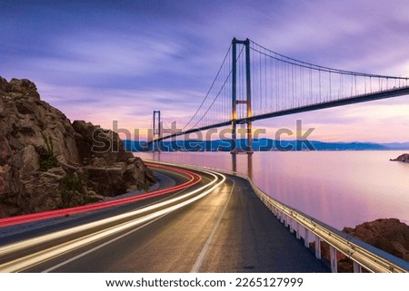 Car lights on the coastal road show the speed in traffic. Fast car on the road. highway landscape at colorful sunset. Road view on the sea. Bosphorus bridge view with road landscape in night travel.