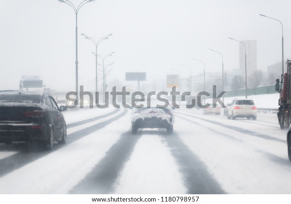 Car with lights on a\
snow covered road.