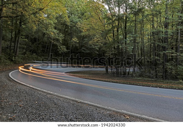 Car lights
streak along the road around a
curve.