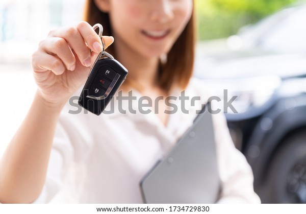 Car loan, contract\
agreement,buying and rent car concept, Saleperson holding car key\
on hand